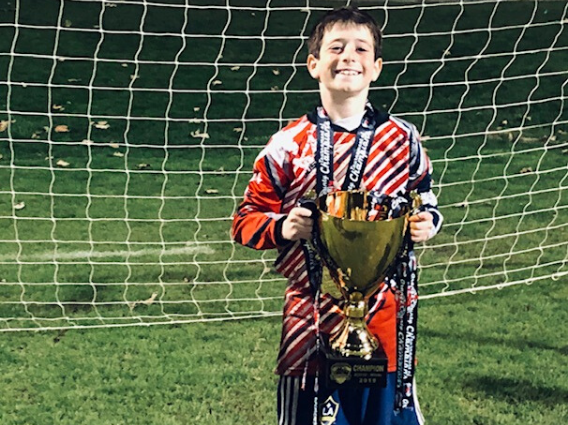 Young Boy stands in front of a goal with a trophy thanks to CHLA's help with this health